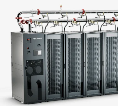A modern industrial cooling unit with multiple vertical racks, featuring piping and control panels on one side.