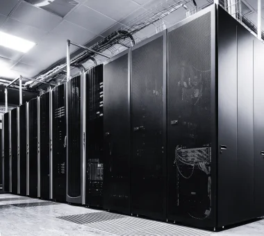 A wide-angle view of a high-density data center room featuring rows of sleek, black server racks integrated with liquid cooling infrastructure to support high-performance computing (HPC) and AI workloads.